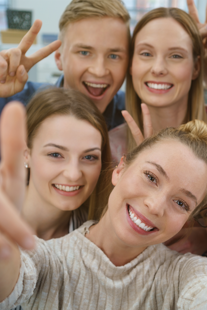 Gruppe von vier Personen, die jeweils mit einer Hand ein Peace-Zeichen zeigen